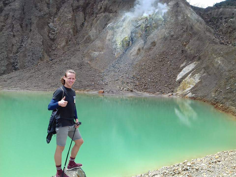 Traveller beside the green crater lake at Mount Papandayan